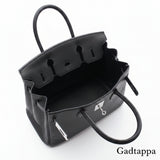 Close-up of a black leather bag with visible stitching on a white background